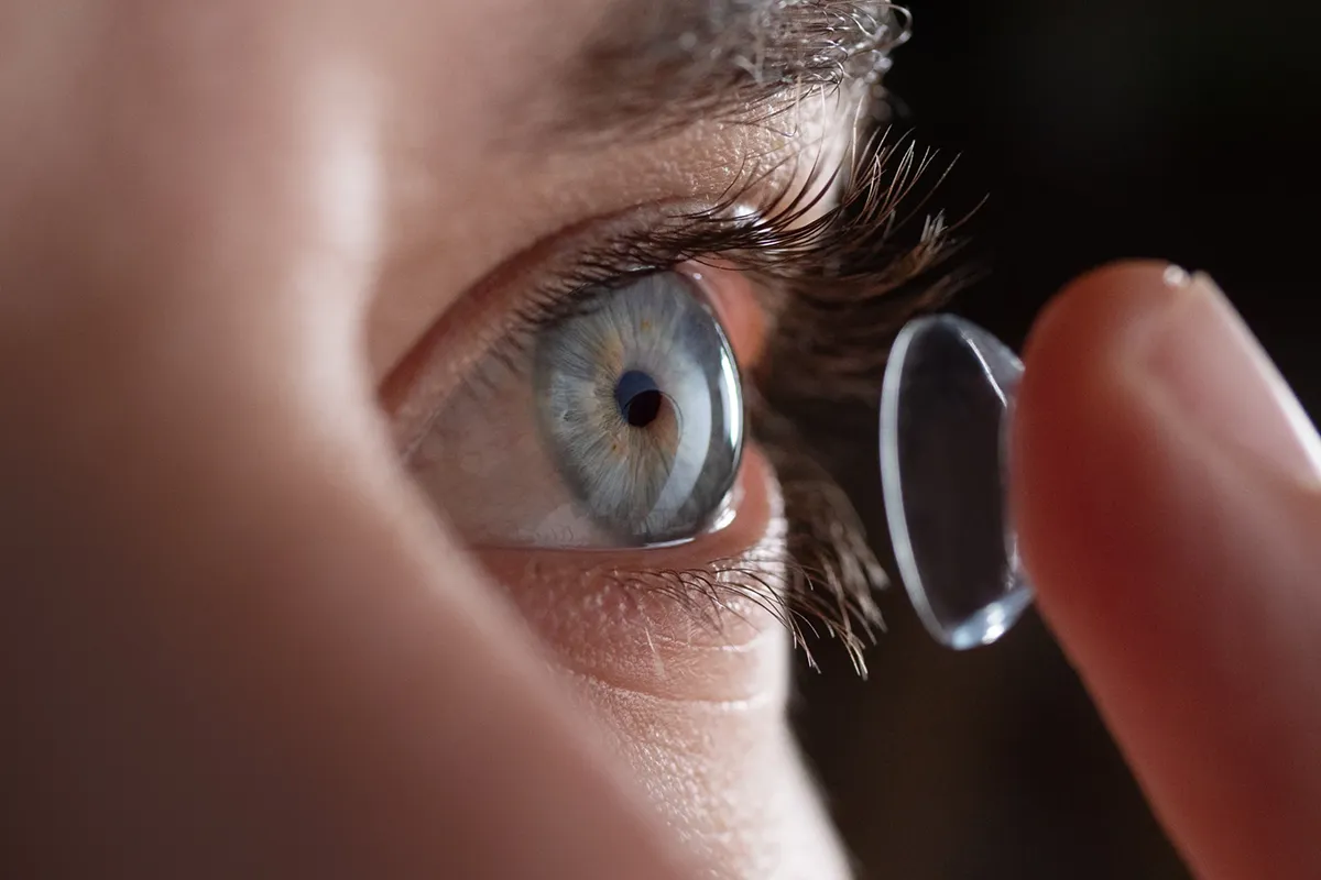 A close-up of a woman's eye as she puts in a contact lens.