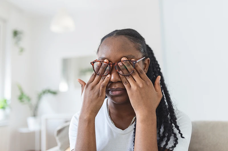 a young woman rubbing her tired eyes underneath her glasses
